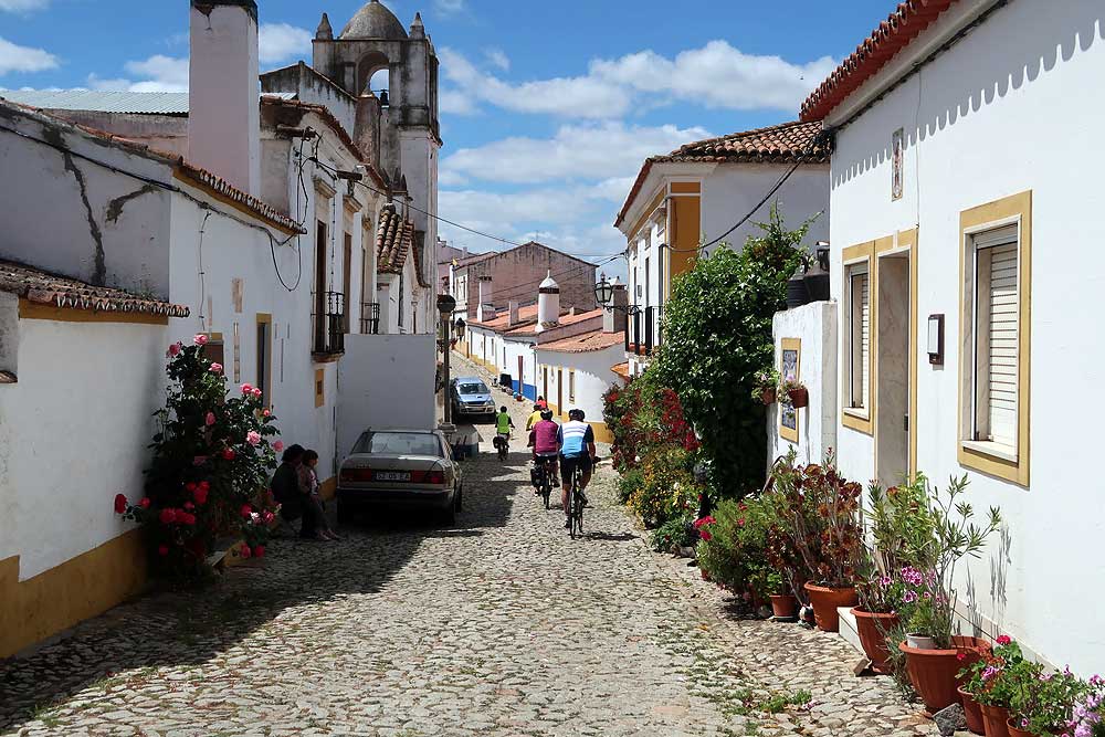 Group of friends cycling along a cobbled road in an Alentejo village in Portugal